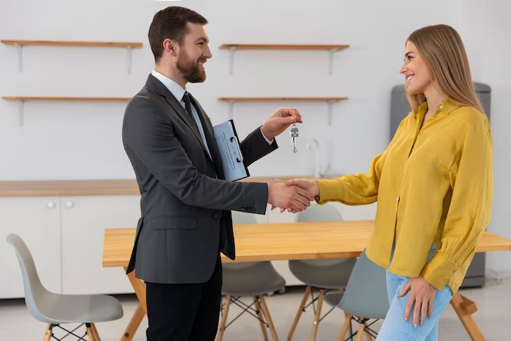 A salesman handing over the keys to an entrepreneur after she successfully purchases a commercial property
